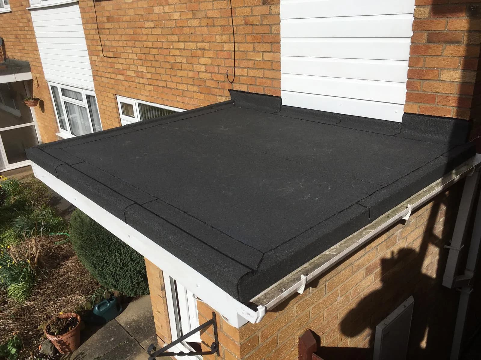 A neat black felt flat roof over a single-storey bay, with newly fitted white fascia board and guttering along the eaves.